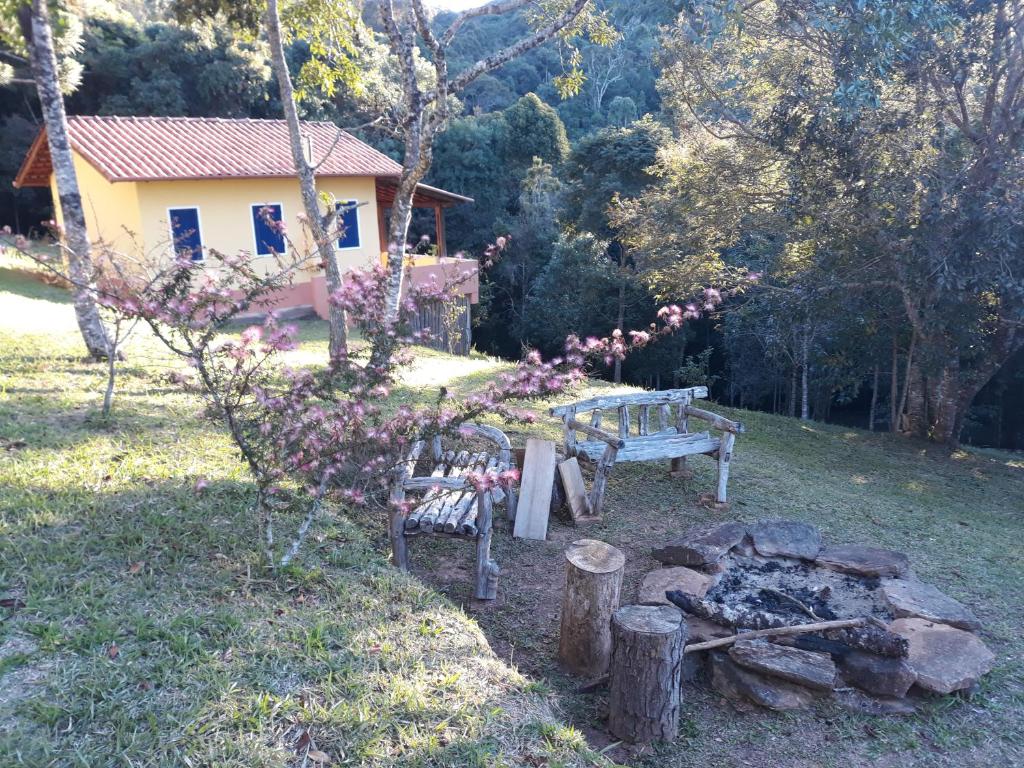 a picnic table and a bench next to a fire at Chalés Serrinha do Papagaio in Aiuruoca