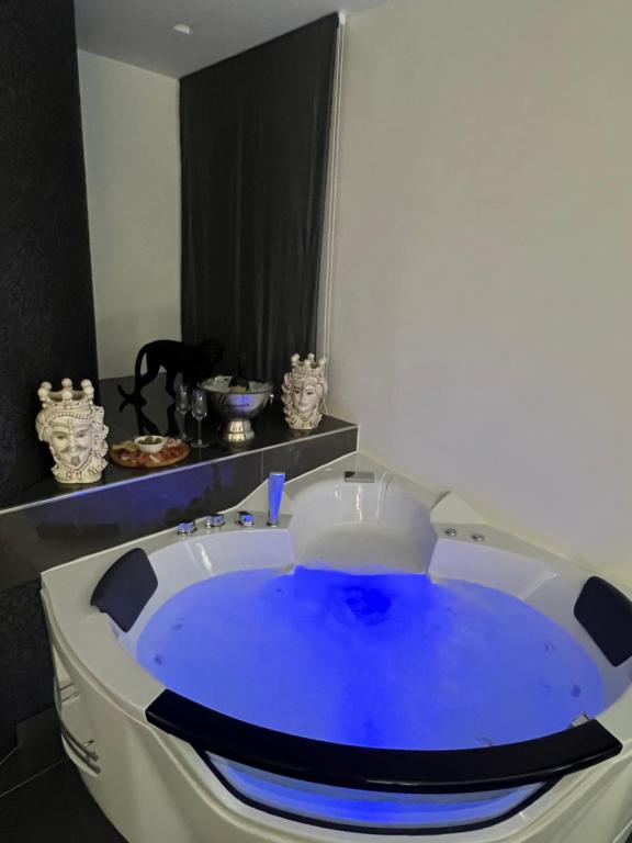 a bath tub with blue water in a bathroom at Musumeci's suite Caltagirone in Caltagirone