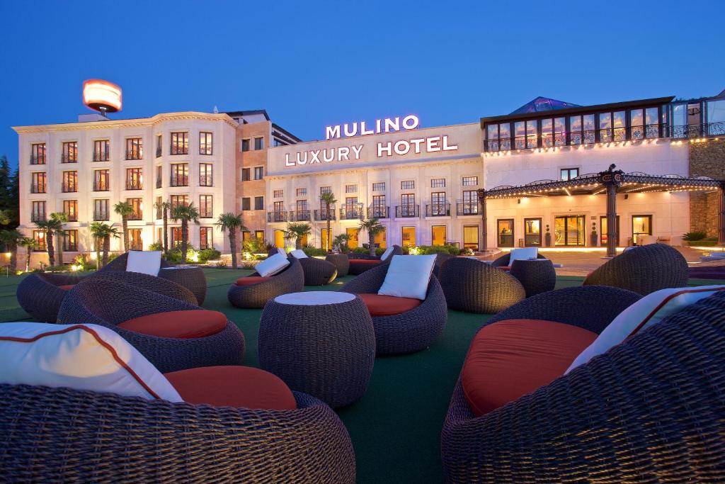 a hotel with wicker chairs in front of a building at Mulino Luxury Boutique Hotel in Buje