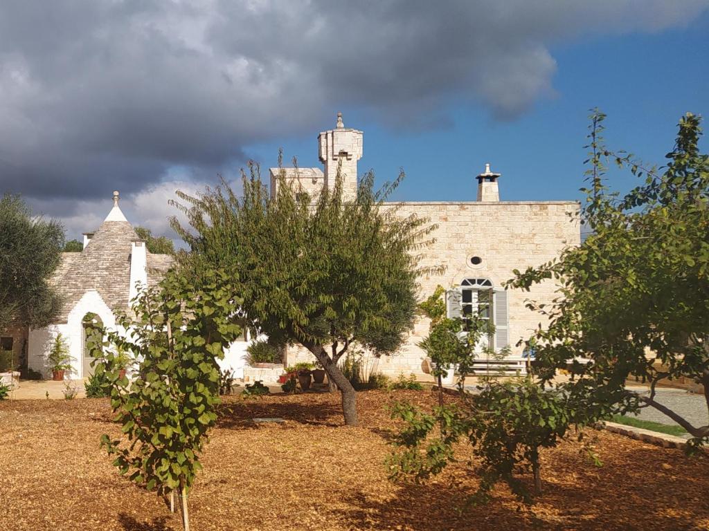 a large stone building with trees in front of it at Masseria - Trulli Genius Loci Dimore in Monopoli