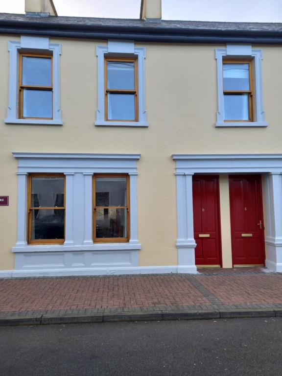 a house with two red doors on a street at Town Square Holiday Homes in Lisdoonvarna