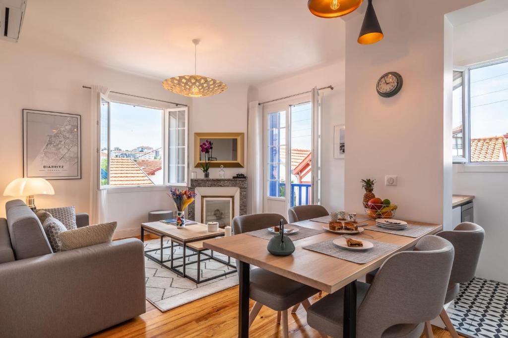 een woonkamer met een tafel en stoelen en een open haard bij Superbe appartement plein de charme à 5min de la plage in Biarritz