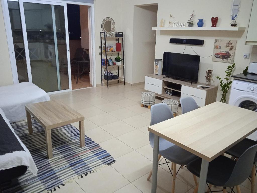 een woonkamer met een tafel en een televisie bij Xylophagou Larnaca Ayia Napa 1 bedroom apartment in Xylophaghou