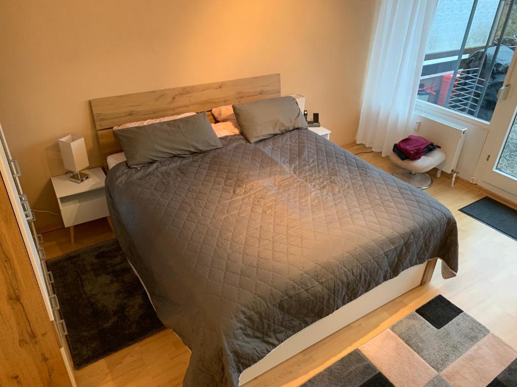 a bedroom with a bed with a gray comforter and two windows at Appartement mit herrlicher Aussicht übers Murgtal in Baiersbronn