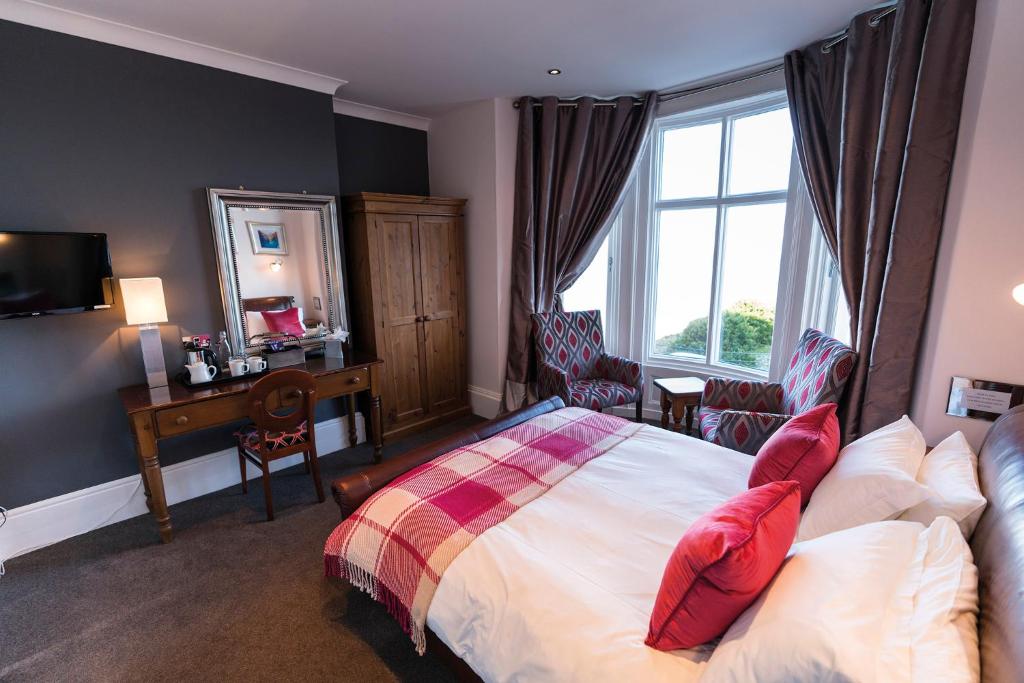 Un dormitorio con una cama con almohadas rojas y una ventana en The Helaina, en Scarborough