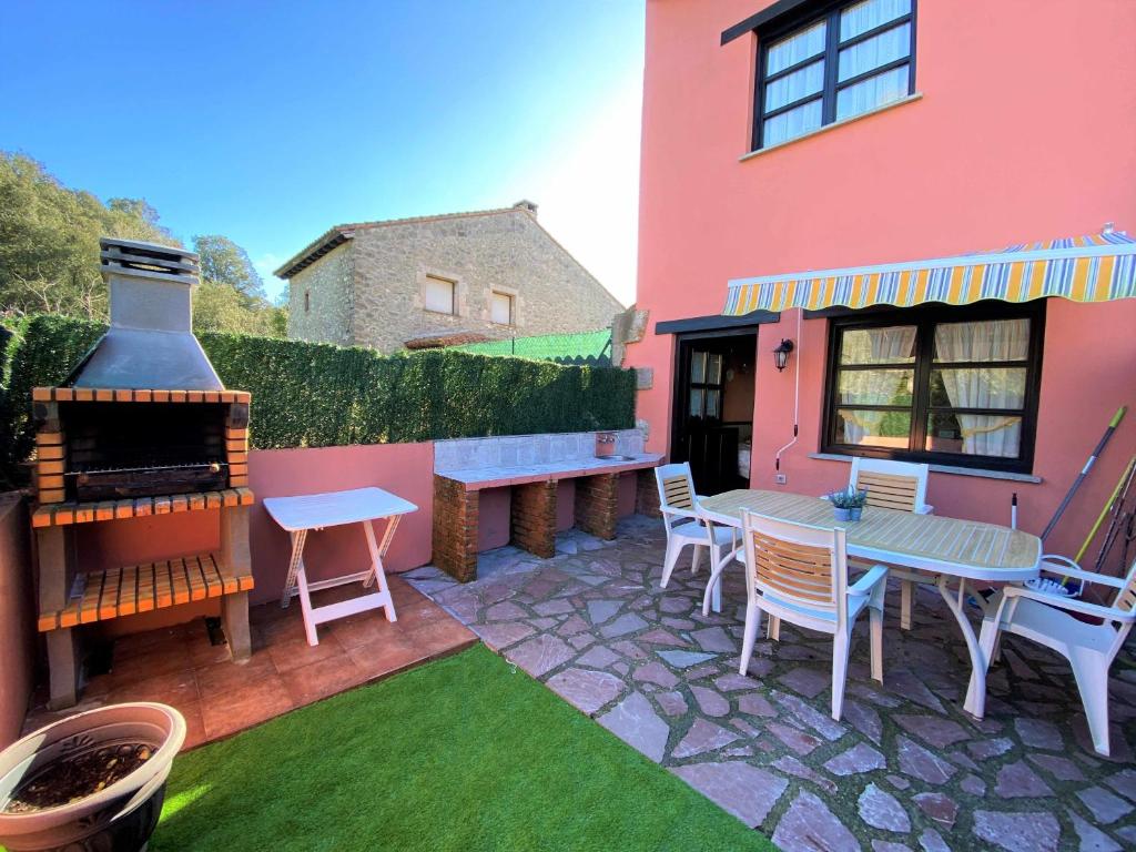 un patio con mesa y sillas junto a una casa rosa en Casa Las Hortensias Quintana, en Llanes