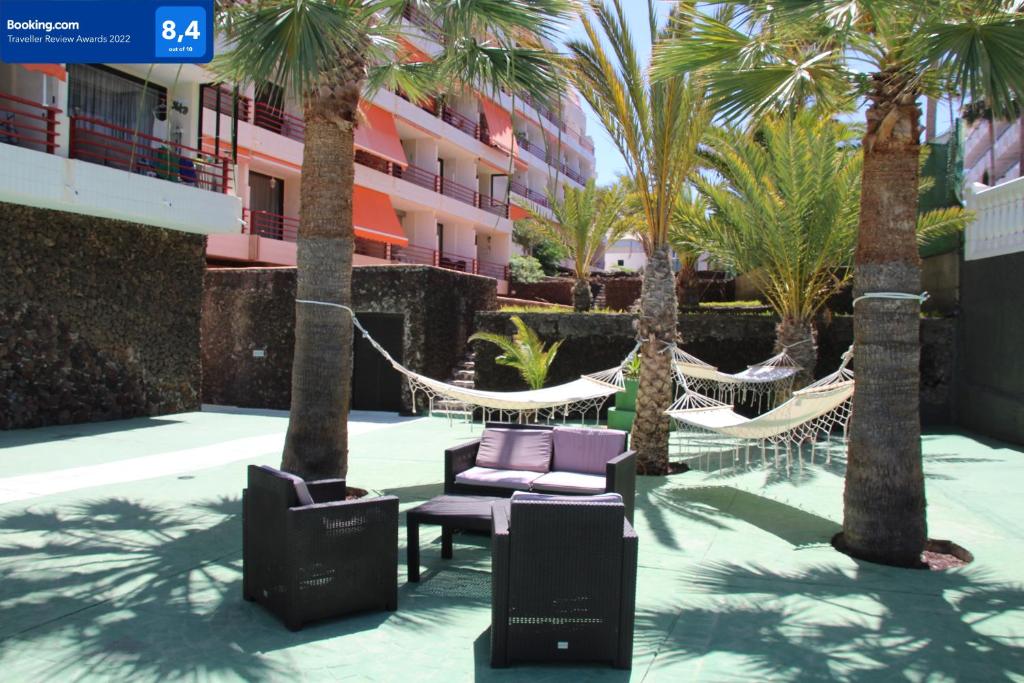 un patio con amache e palme e un edificio di Holiday in Olympia a Playa de las Americas