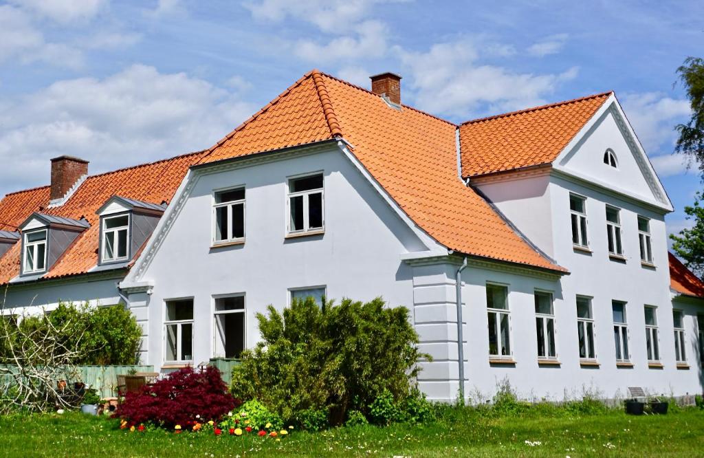 ein großes weißes Haus mit orangefarbenem Dach in der Unterkunft Old Roses Guesthouse in Broager