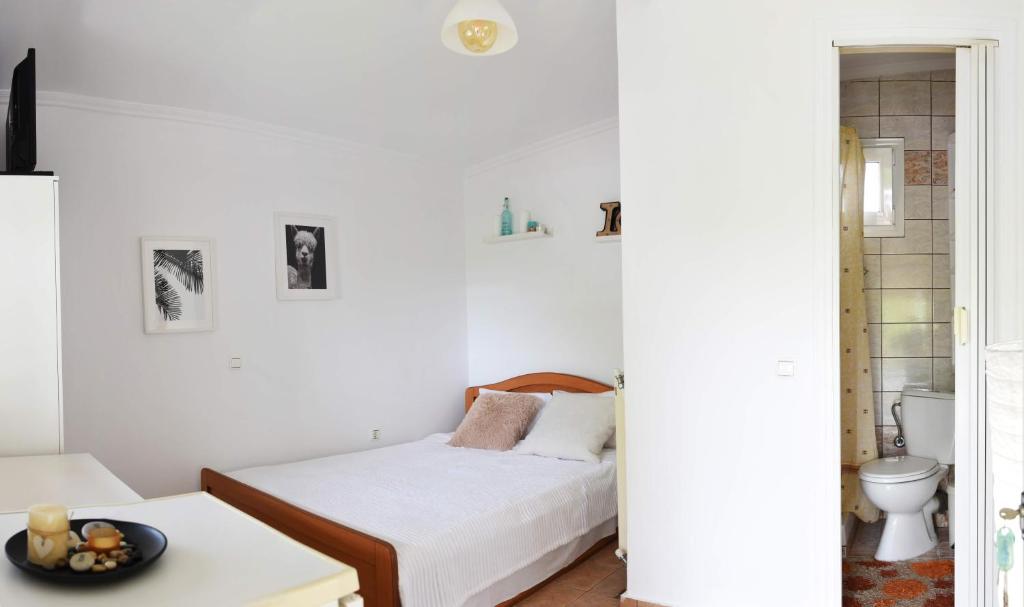 a white bedroom with a bed and a table at Summer Panorama first floor Studio in Epanomi