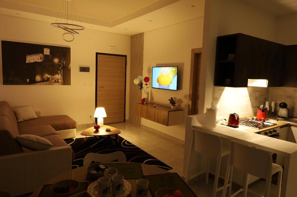 een woonkamer met een bank en een keuken met een tv bij B&B Acquedotto in Corigliano Calabro