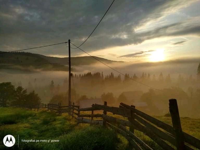 a fence in a field with the sun in the background at Casa Sașilor in Arieşeni