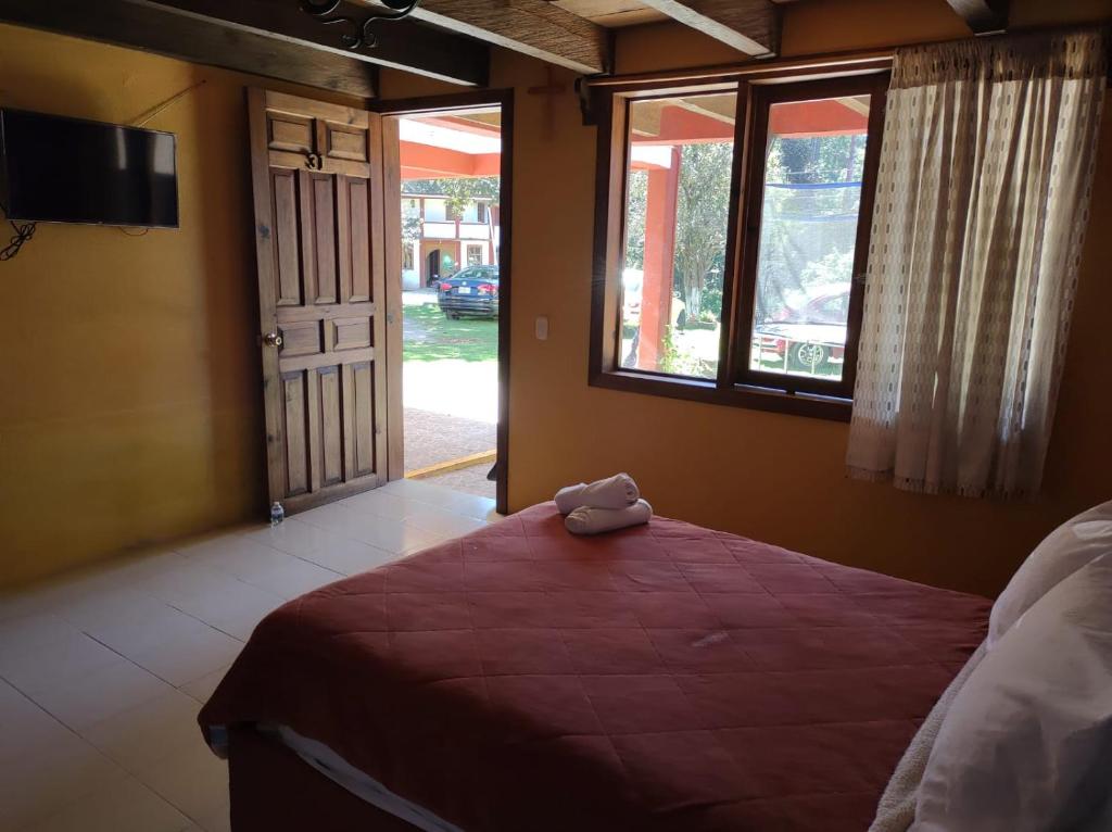 a bedroom with a bed and a window at Hotel Campestre Las Flores in San Cristóbal de Las Casas