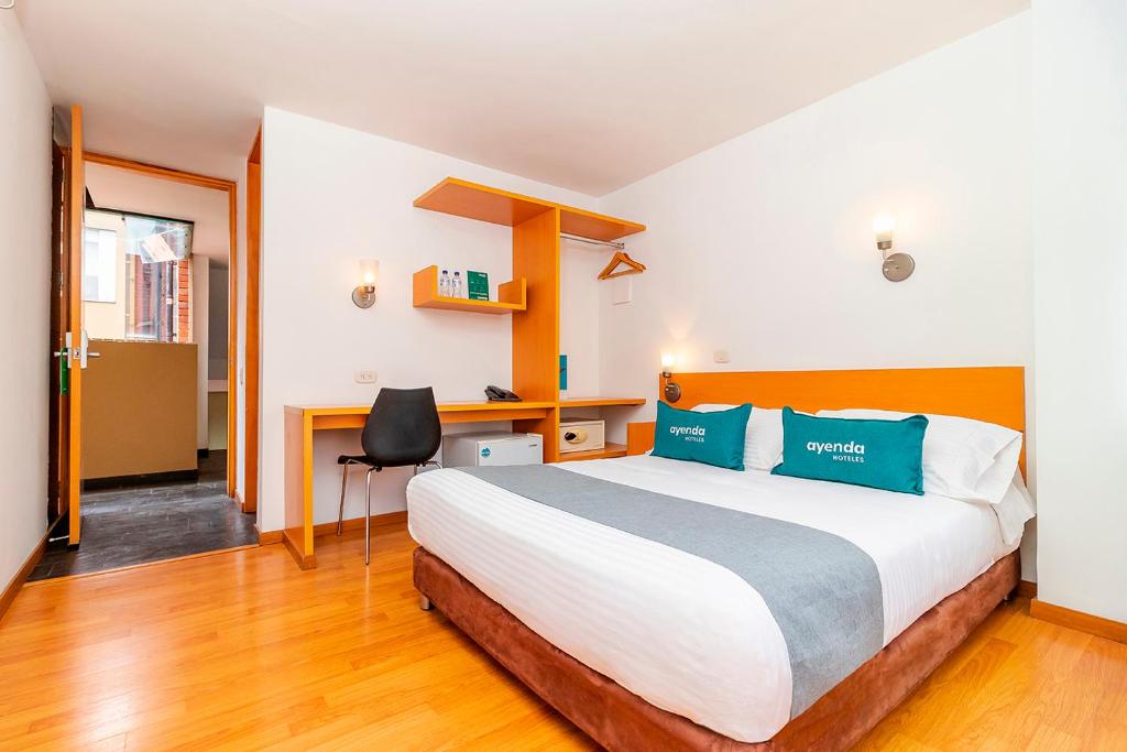 a bedroom with a large bed and a desk at Ayenda Abitare 56 in Bogotá