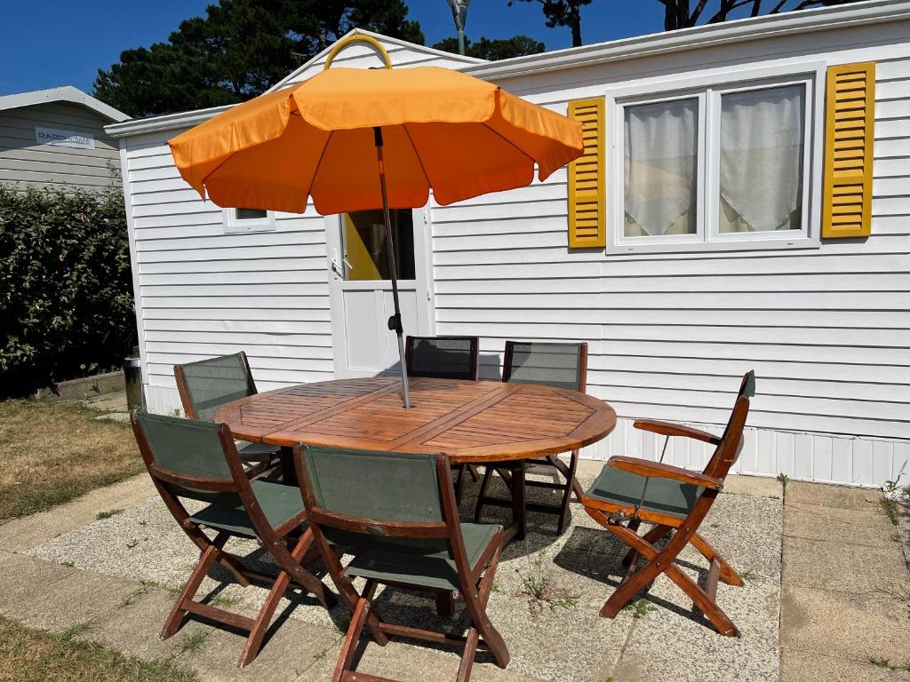 un tavolo in legno con sedie e ombrellone di MobH Comfy a Dinard