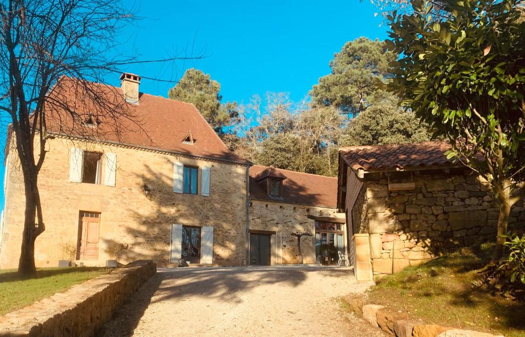 une ancienne maison en pierre avec un arbre et une allée. dans l'établissement L'écrin des symes, à Simeyrols