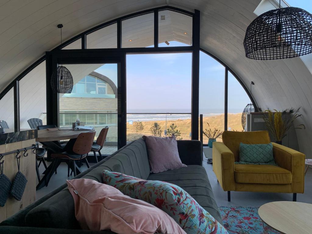 una sala de estar con un sofá y una mesa en Penthouse Witsand Zeezicht, en Egmond aan Zee