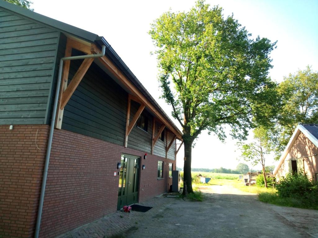 a barn with a tree next to a building at B&B In de Wei in Erp