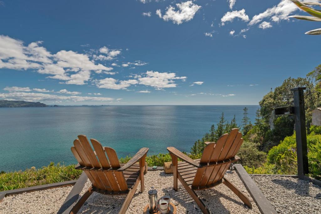 - deux chaises assises sur une terrasse donnant sur l'océan dans l'établissement Oceana Heights Paradise - Beautiful 2 bdrm self contained apartment, à Tairua