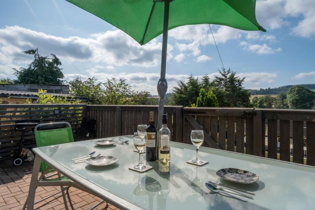 a table with a green umbrella and wine glasses at The View Brechin in Brechin