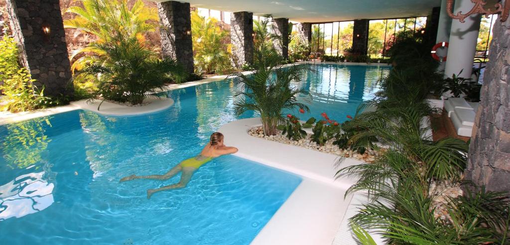 Eine Frau schwimmt im Pool in der Unterkunft La Palma Jardín Resort in El Paso