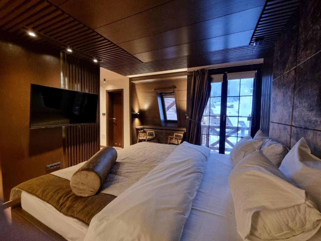 a large bed with white sheets and pillows in a bedroom at Apartman 301-Aparthotel Vučko Jahorina-private host in Jahorina