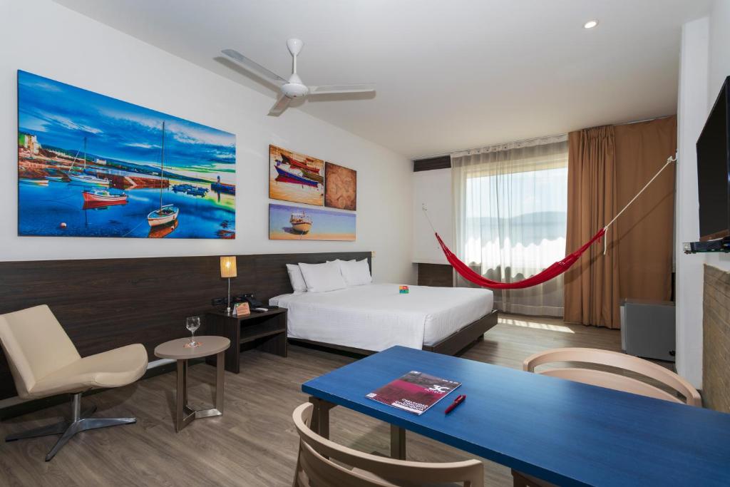 a hotel room with a bed and a table and chairs at Pop Art Hotel CLC Puerto Mamonal Cartagena in Cartagena de Indias