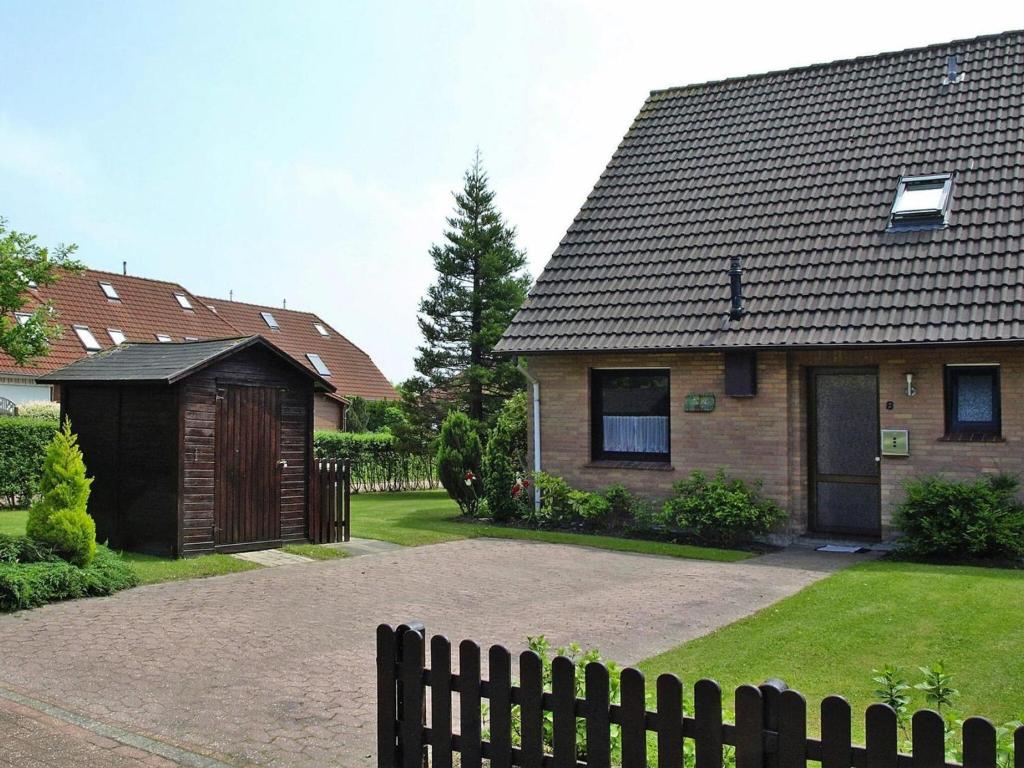 ein Haus mit einem Zaun vor einem Hof in der Unterkunft Terraced house, Nessmersiel in Neßmersiel