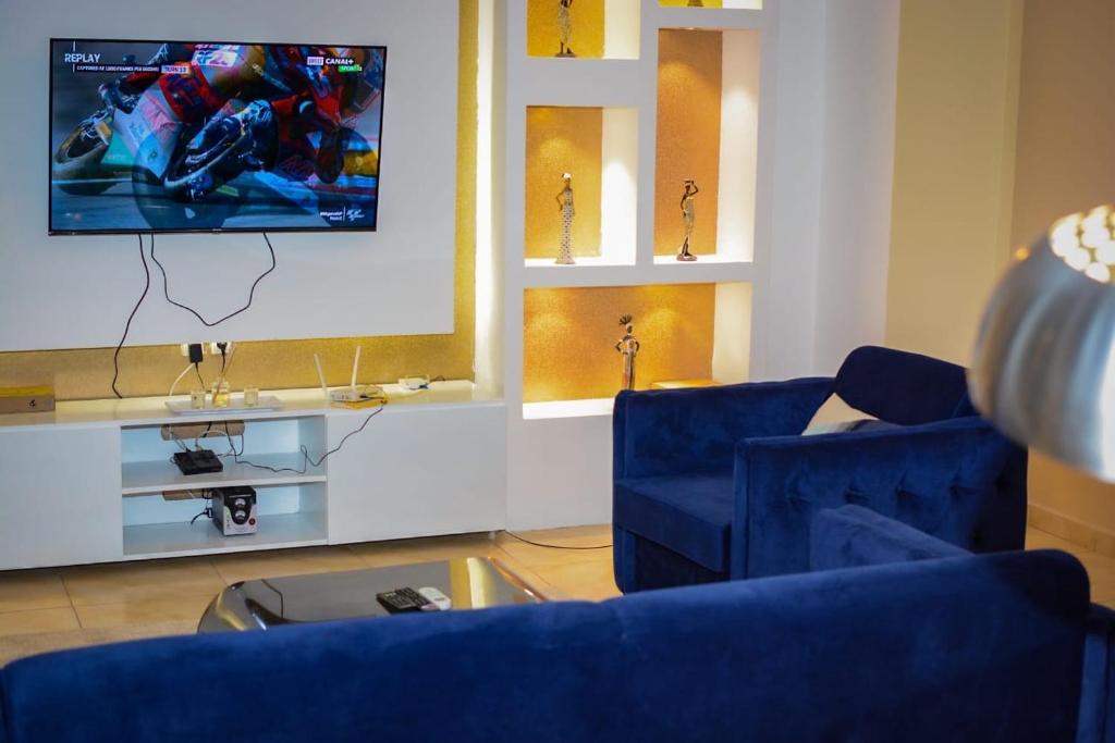 a living room with two blue chairs and a tv at Appartement Cosy 3 bonapriso in Douala