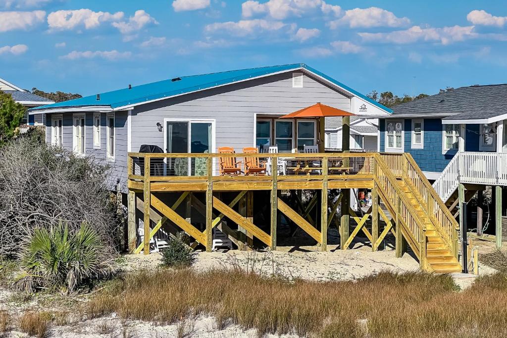 a house with a wooden deck on the beach at Dock Holiday in Oak Island