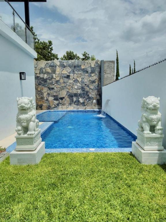ein Schwimmbad mit zwei Statuen in einem Hof in der Unterkunft Casita Nodin in Cuatrociénegas de Carranza
