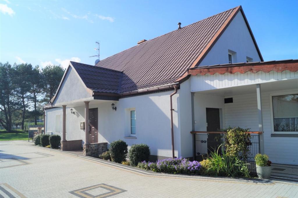 una casa blanca con techo de metal en una calle en MARINKA Grzybowo, en Grzybowo