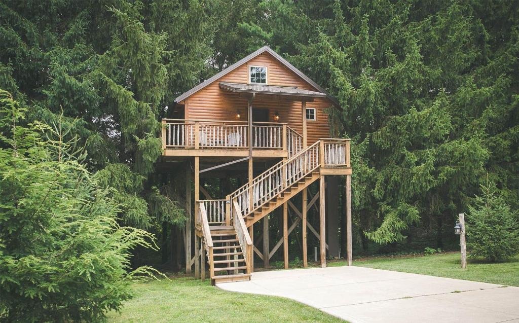 a tree house with a deck and a staircase at Lofty Willows Treehouse by Amish Country Lodging in Millersburg