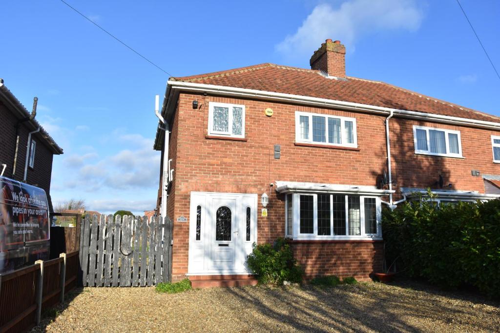 una casa de ladrillo con una puerta blanca y una valla en Stafford House, en Norwich