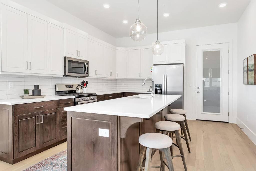 a white kitchen with a counter and stools in it at Villa 19 - LUXURY GOLF VILLA, BEST VIEW, YEAR ROUND HEATED POOL & HOT TUB! in St. George