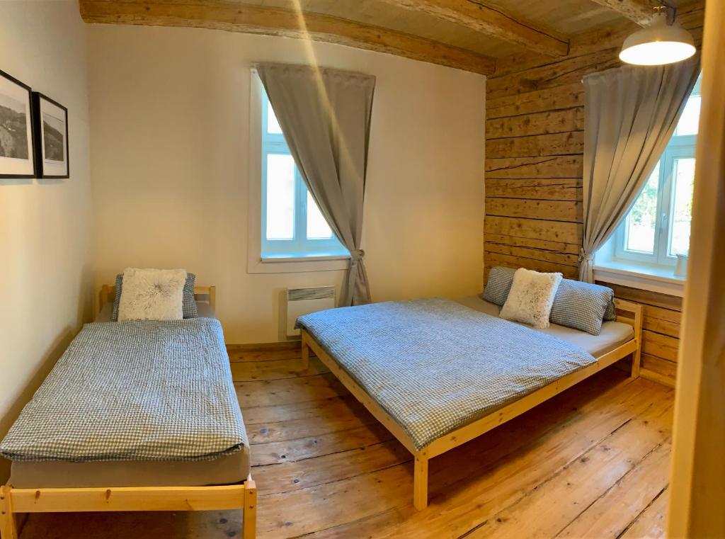 two beds in a room with wooden floors and windows at Chata Klášter in Hraběšice