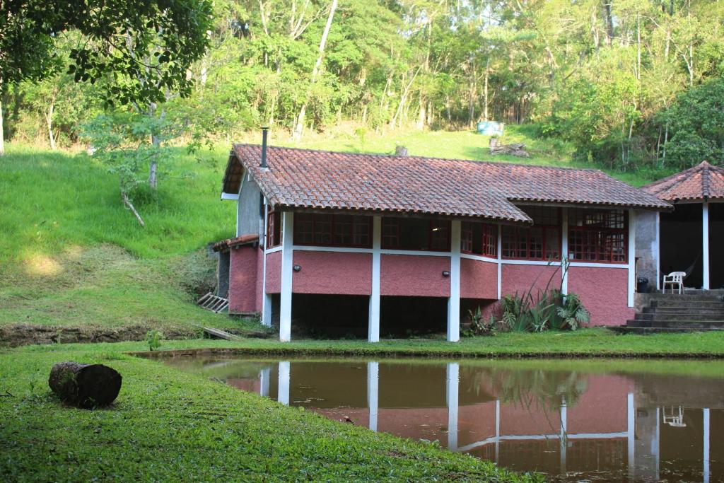 a red and white house next to a body of water at Chalé 4x4 alto da serra de Sao Roque. in São Roque