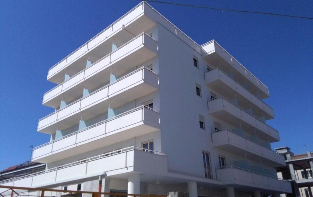 - un bâtiment blanc avec des balcons sur le côté dans l'établissement Nuovo HOTEL SETTIBI 20m dalla spiaggia, à Giulianova