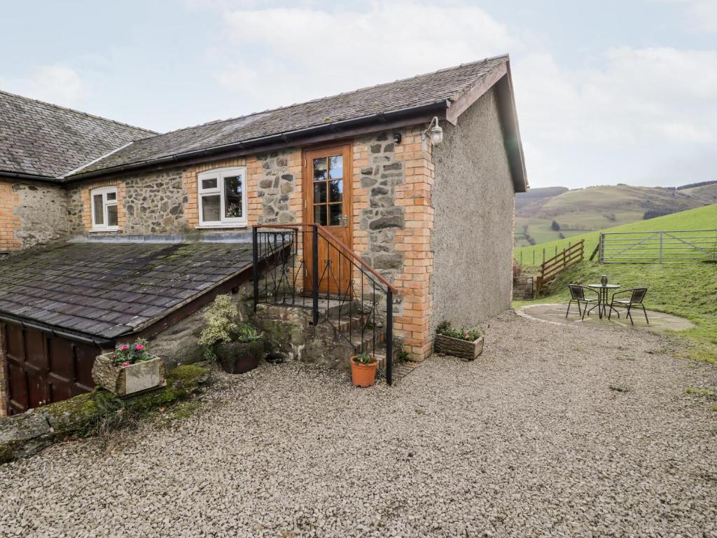 a stone house with a balcony and a table at Peniarth in Pen-y-bont-fawr