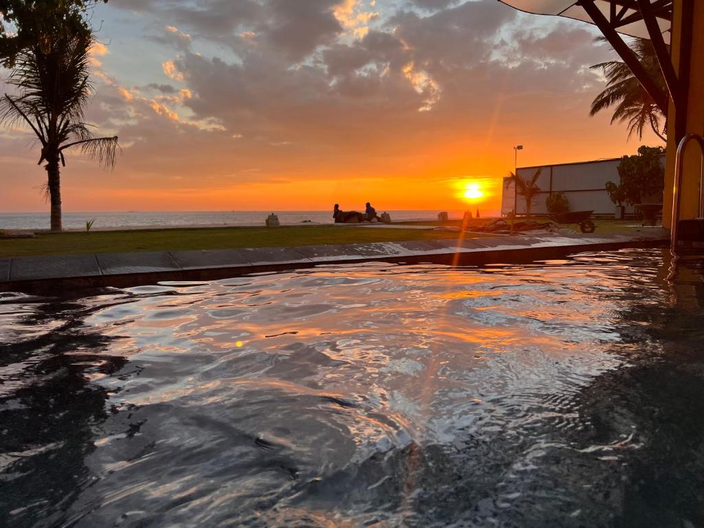 a swimming pool with the sunset in the background at Amanda Beach Villas in Unawatuna