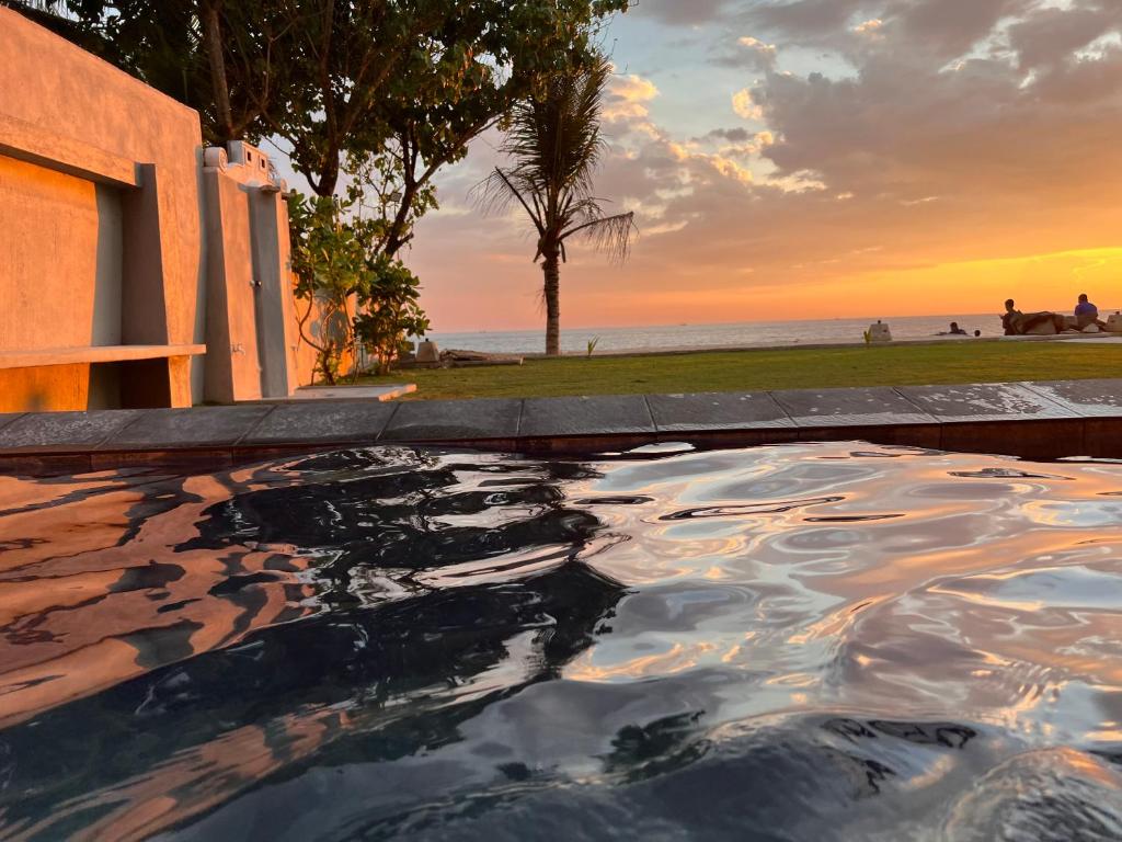 a swimming pool with a sunset in the background at Amanda Beach Villas in Unawatuna