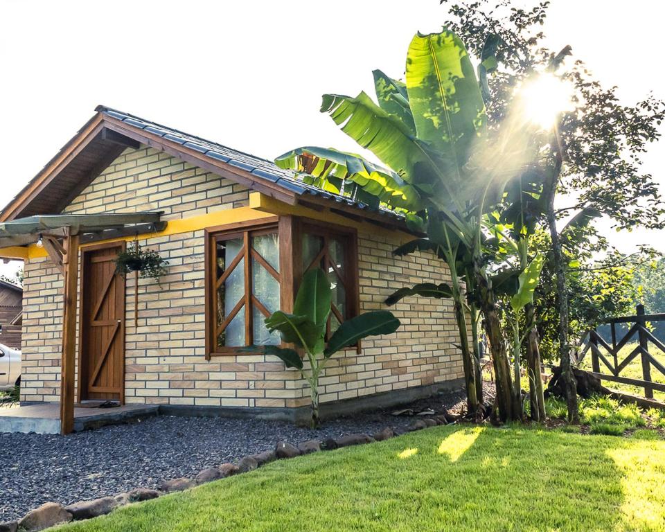 una pequeña casa de ladrillo con un árbol delante de ella en Chalé Girassol en Praia Grande