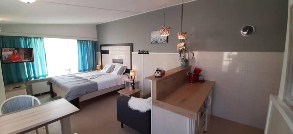 a hotel room with a bed and a desk and a room with a bed istg at Appartement Duinzee Texel in De Koog