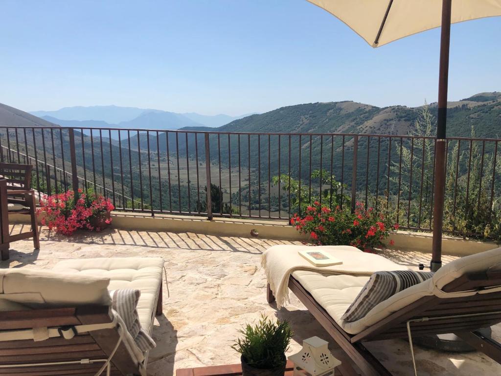 a balcony with chairs and an umbrella and a view at Il Terrazzo in Santo Stefano di Sessanio
