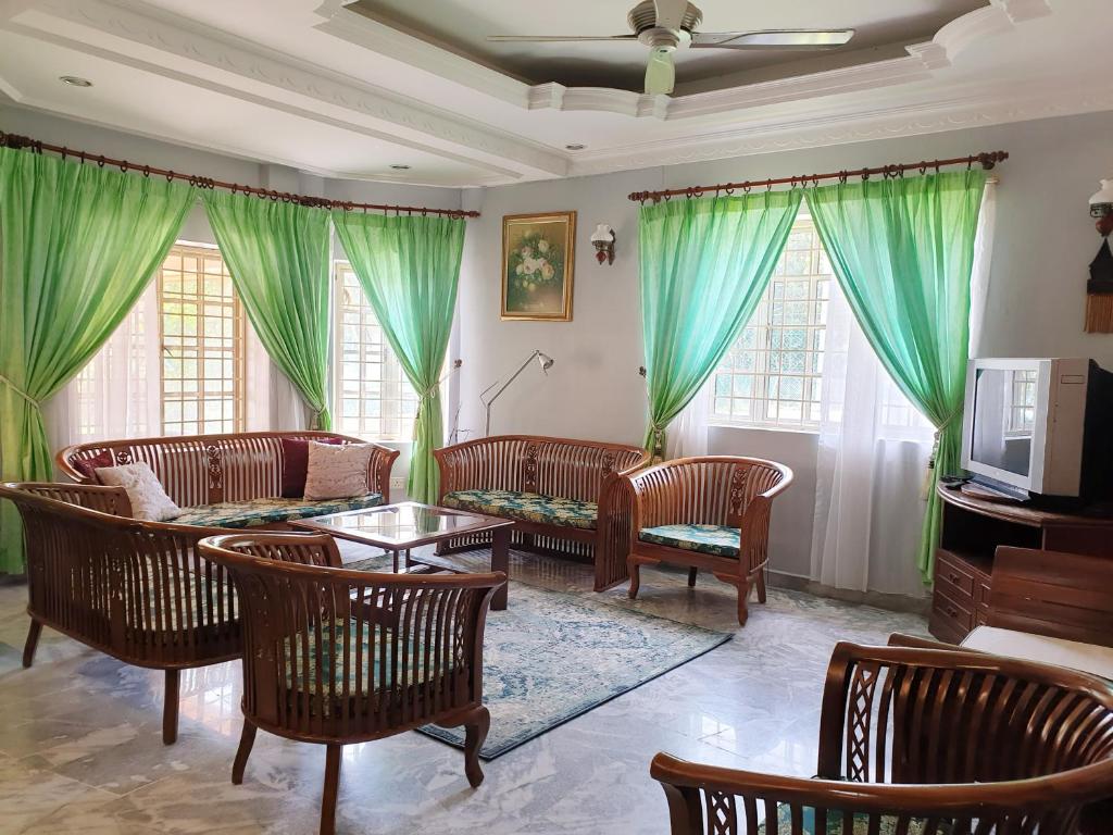 een woonkamer met groene gordijnen en een bank en stoelen bij Lavender Impian Homestay in Kajang