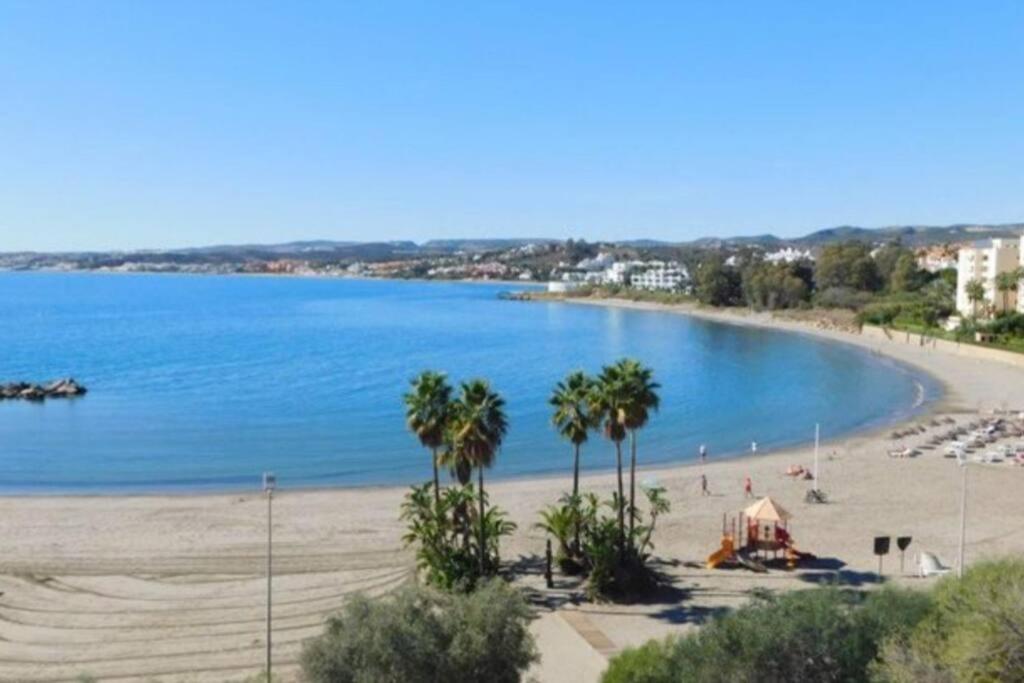 einen Strand mit Palmen und einem großen Wasserkörper in der Unterkunft Estepona port beachside apartment - Marina Bay in Estepona