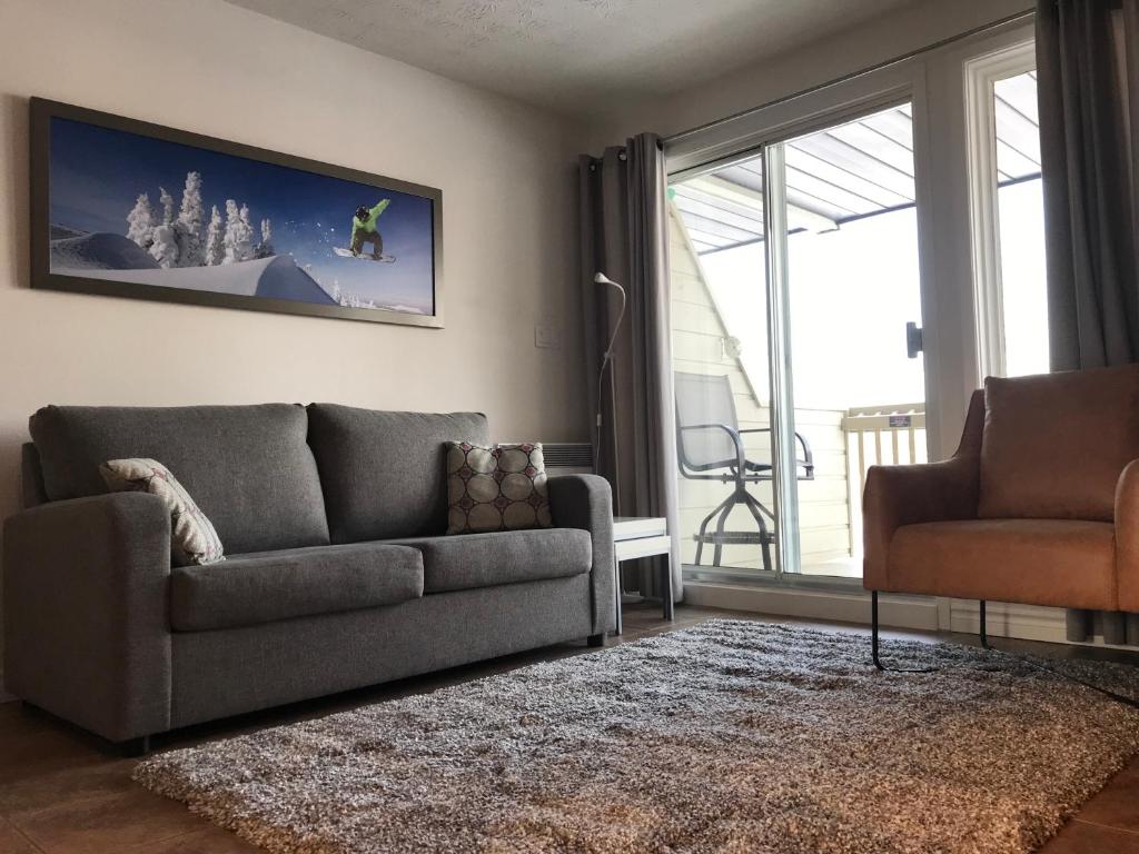 a living room with a couch and a chair at Magog Waterfront Condo in Magog-Orford