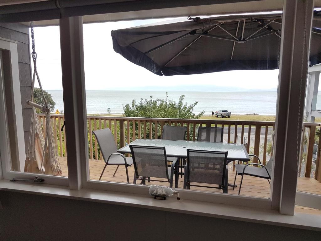 un tavolo e sedie su un balcone con vista sulla spiaggia di Coromandel Tapu - Beachfront Escape a Tapu