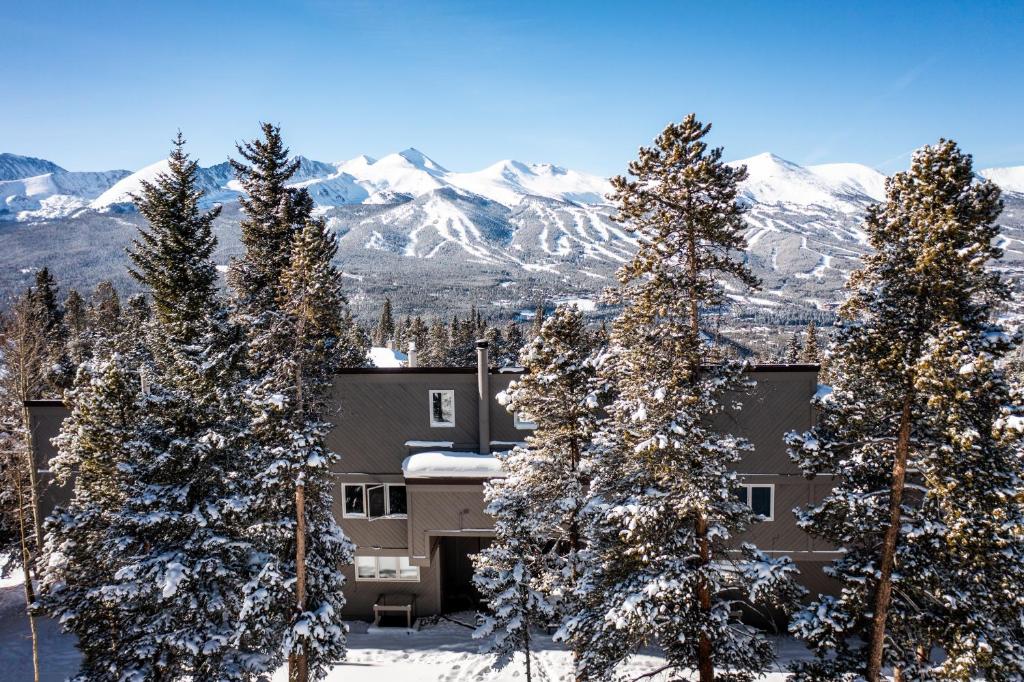 a building with snow covered trees and mountains in the background at Gold Point Resort by Vacatia in Breckenridge