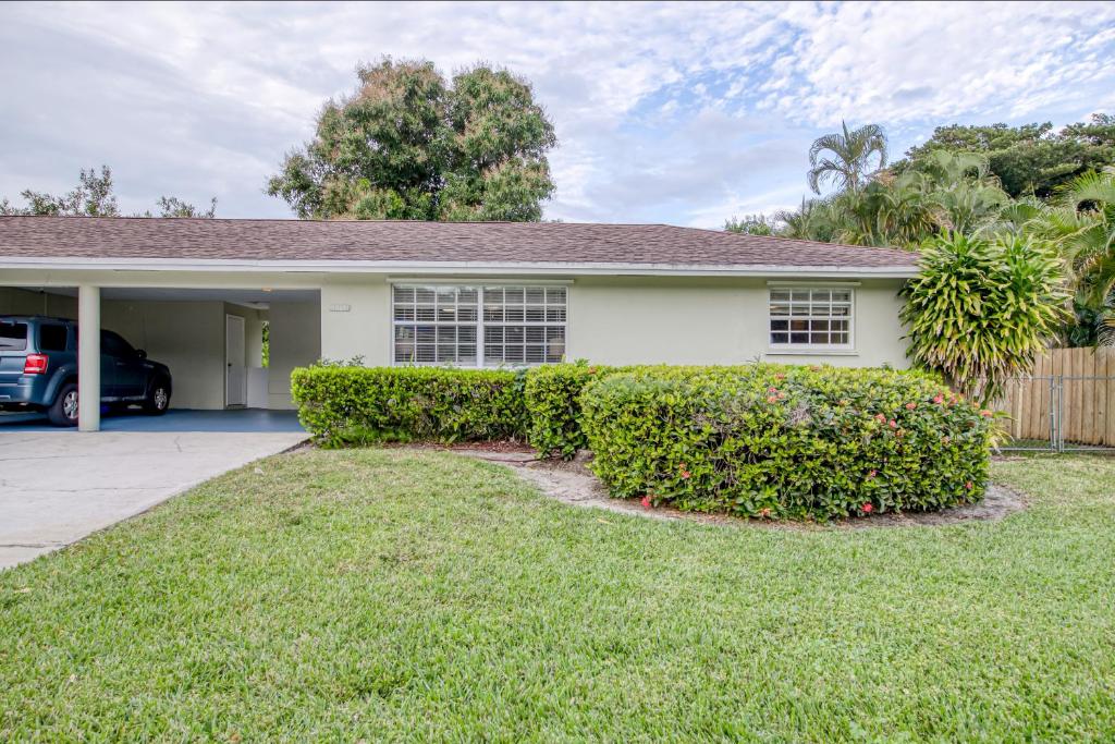 una casa blanca con arbustos delante de un patio en Two Palms B en North Palm Beach