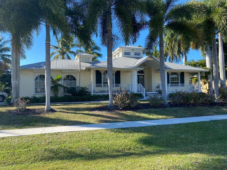 a white house with palm trees in front of it at Windemere on Marco Island. 4 BR waterfront home in Marco Island